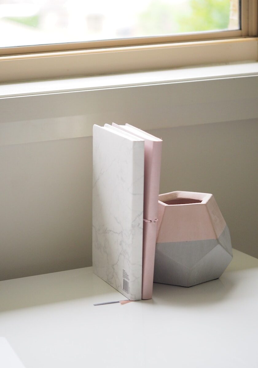 White and Pink Books Piled Beside Pink and Gray Ceramic Vase