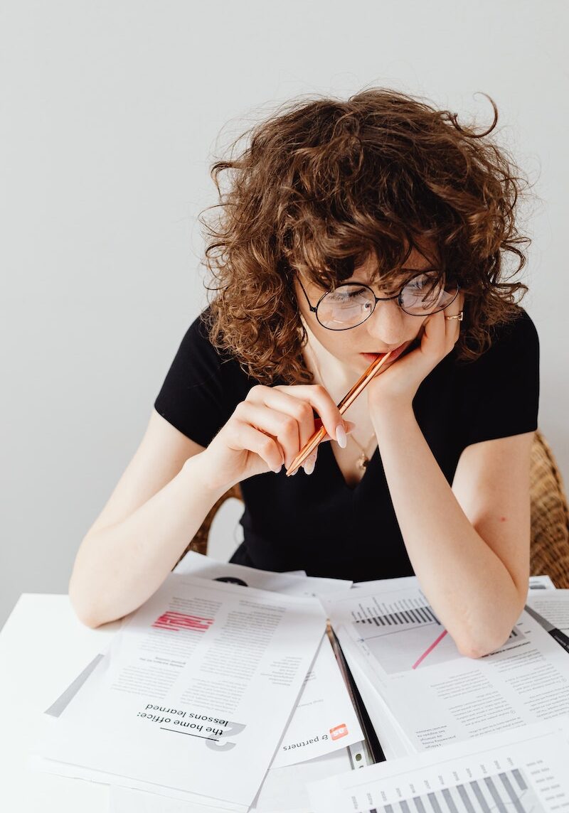 Woman in Black Shirt Wearing Eyeglasses Sitting at Table with Documents