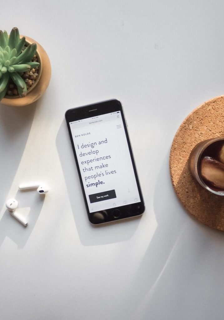 post-2014 iPhone beside Apple AirPods and succulent plant on white surface