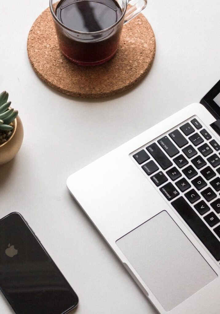 space gray iPhone X beside turned on laptop beside coffee and succulent plant