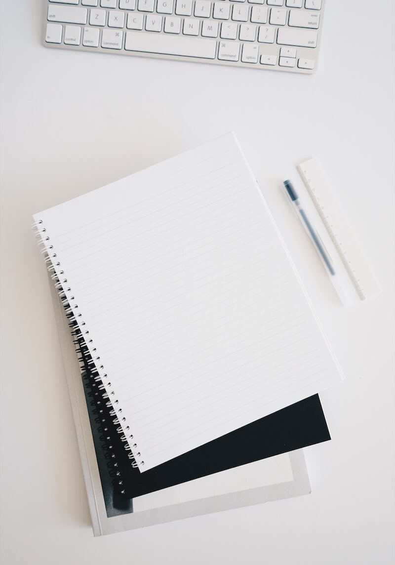 empty spiral notebook near keyboard and pen